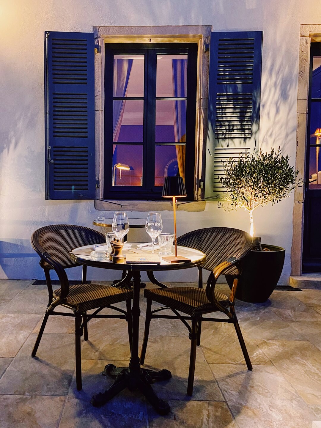 Dos copas de vino sobre una mesa con velas en una terraza nocturna